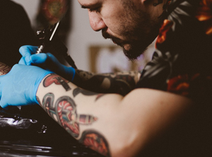 Tattooist with moustache working on a tattoo