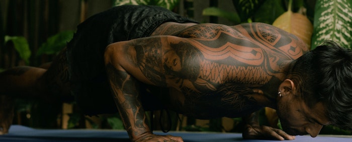 Tattooed man doing pushups.